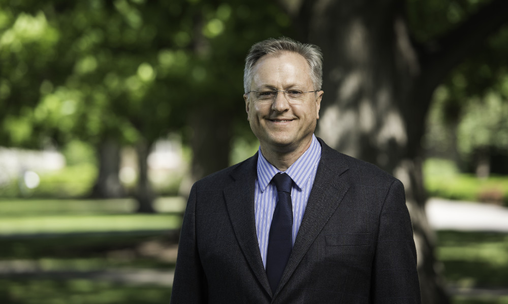 Jeff Runner wears a suit and tie outdoors on the Eastman Quadrangle.