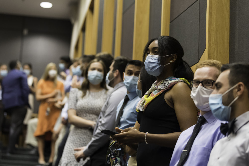 A line of medical students wearing business casual outfits and masks before the ceremony.