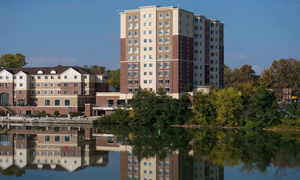Apartment building along river and set against blue sky.