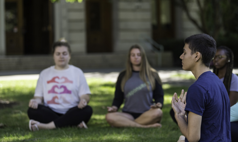 students sit outside to meditate.