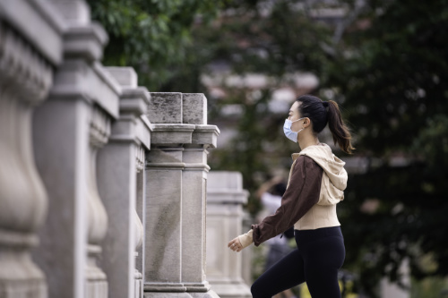 As part of mindful practice, a student in a mask walks up the Eastman Quad steps.