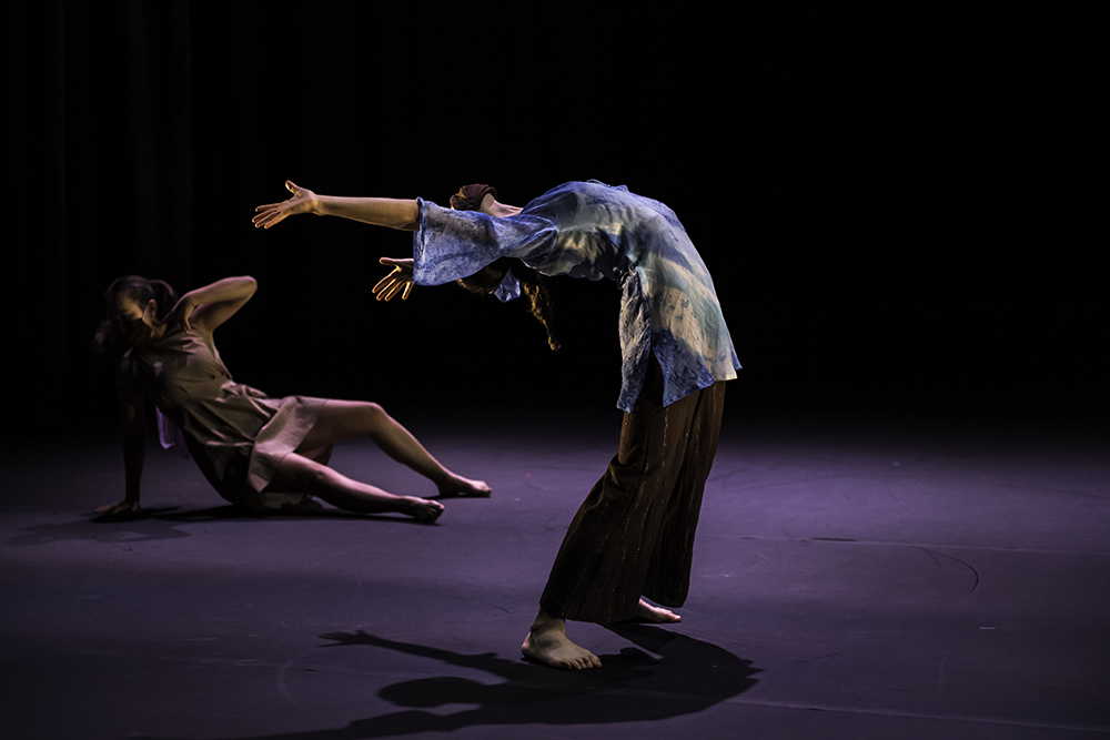dancer in foreground bends backwards while student dances on the ground in background