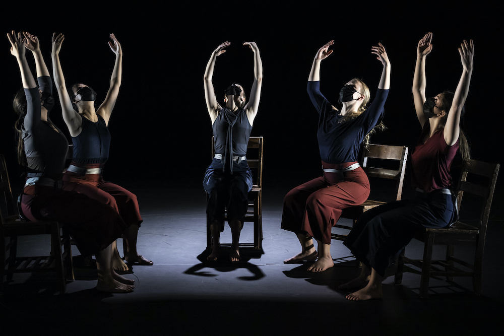 student dancers seated in chairs and raising arms