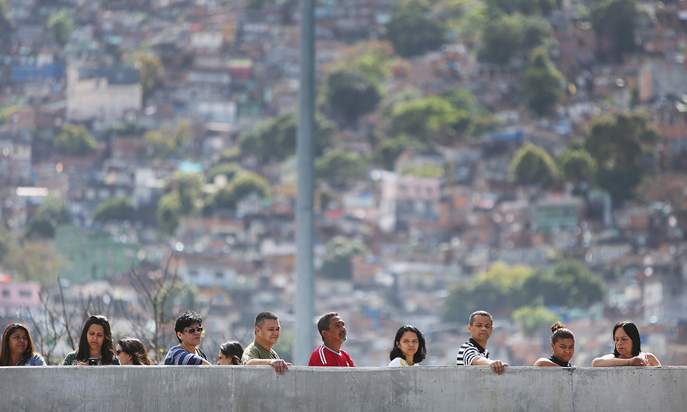 voters lined up behind wall with blurred Rio De Janeiro landscape behind them