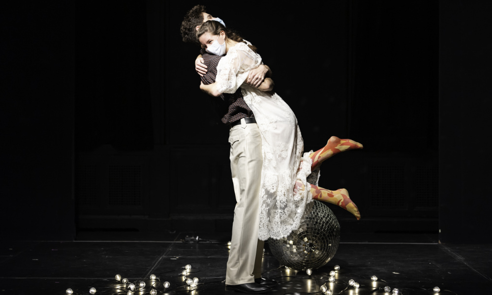 Feature image Man lifts a woman up in an embrace during a performance of Stupid F-cking Bird.