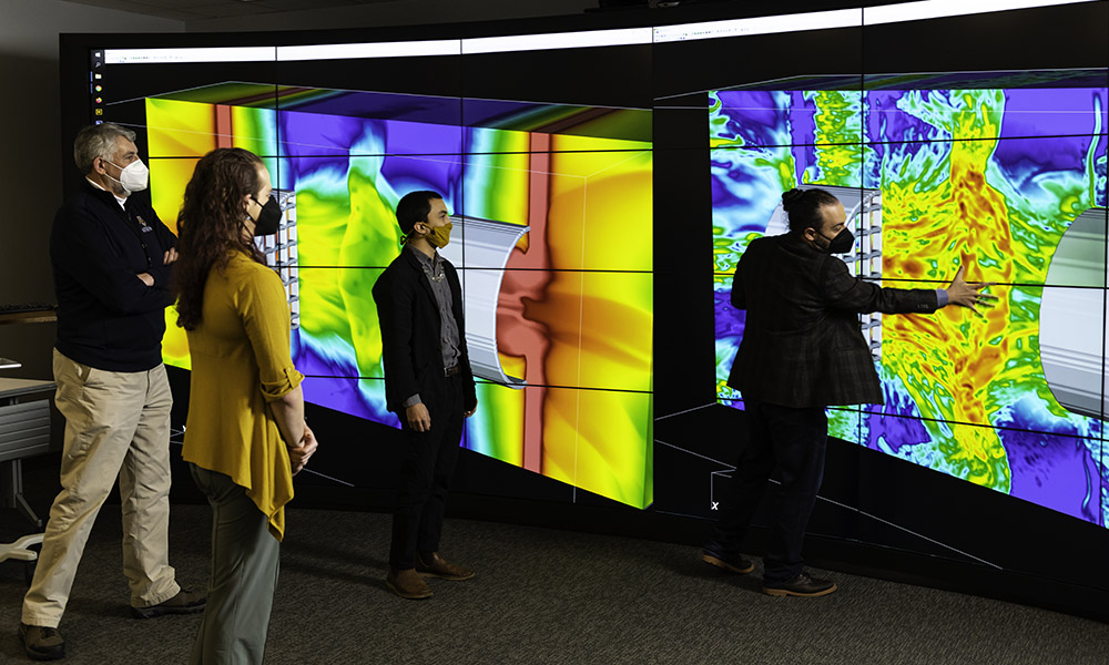 Researchers look on at wall-sized, vividly colored simulation of laser-driven experiment.