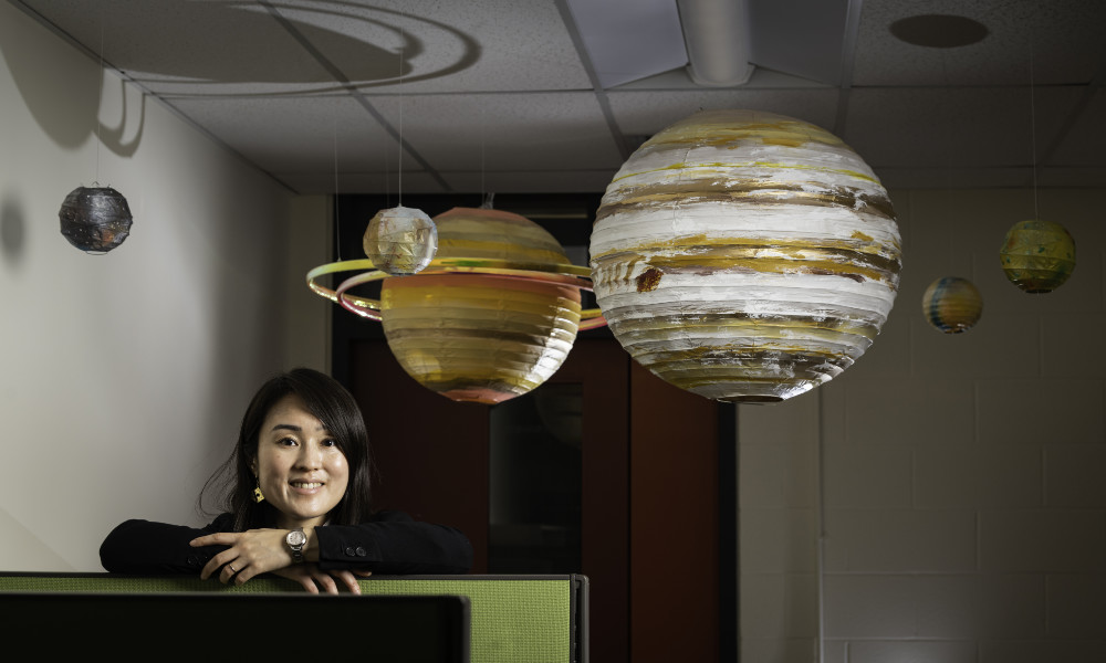 Miki Nakajima in her lab with planet models hanging from the ceiling