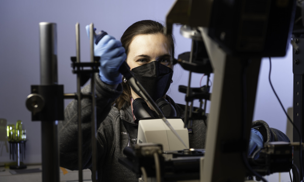 Female optics PhD student with a quantitative phase microscope.