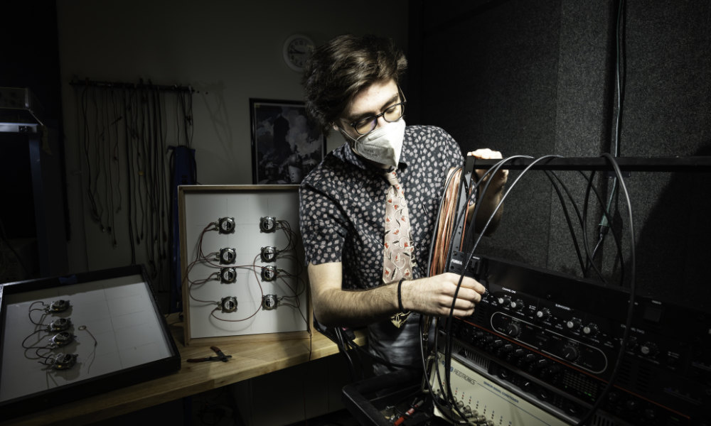 College student in mask adjusts dials as part of a research project using flat panel technology.