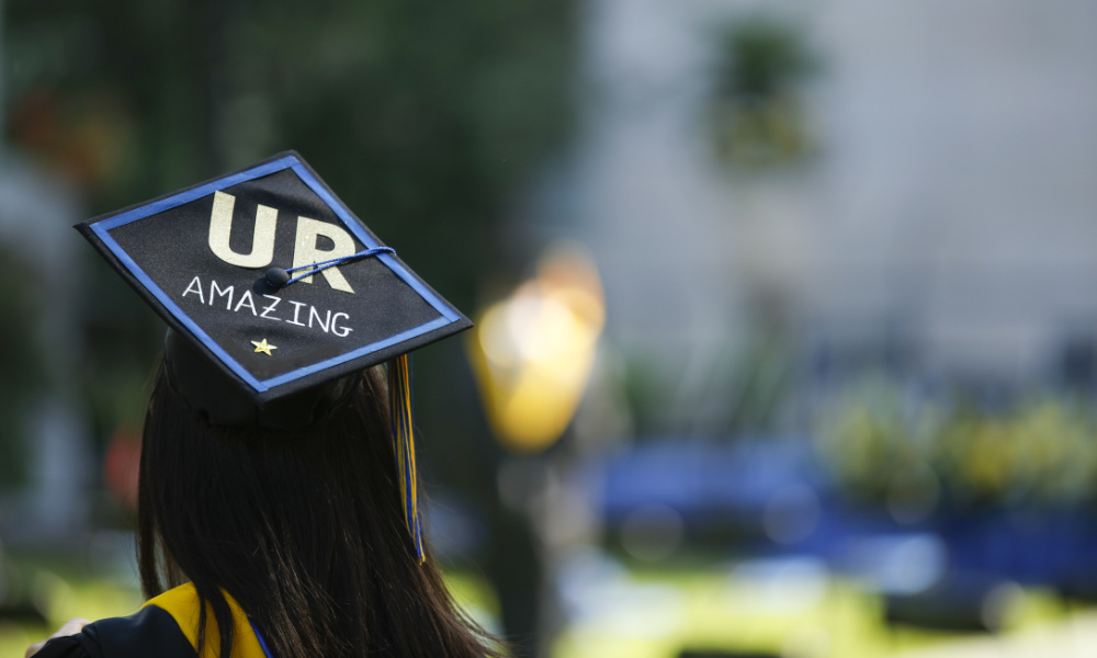 Woman facing away from camera wearing graduation cap with mortarboard that says U-R Amazing.