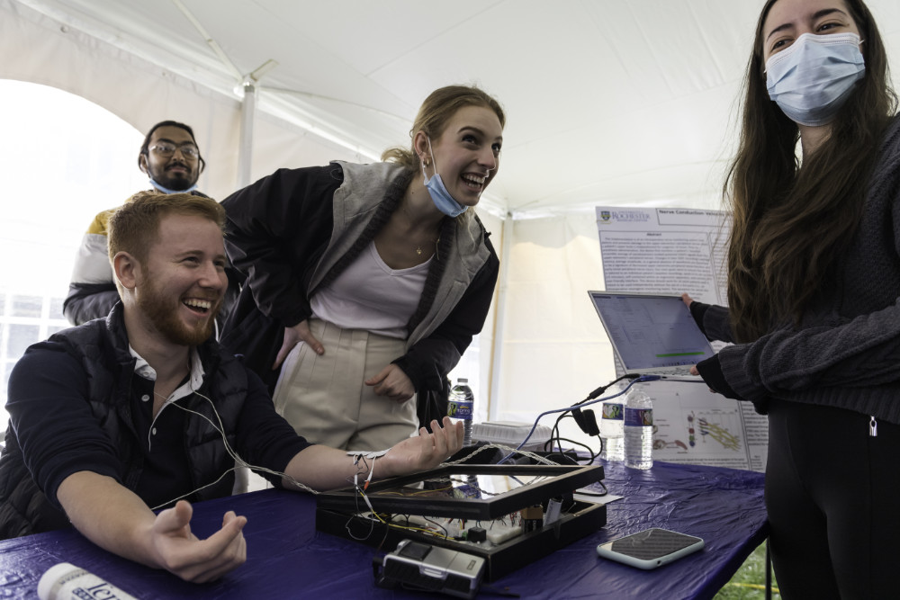 Person hooked up to a measurement device alongside the two student designers of the device.