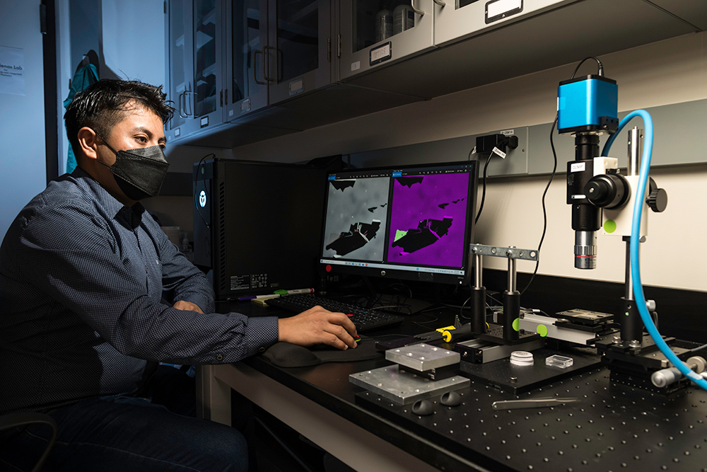 researcher in a lab uses a computer with a microscope with a camera attached. 