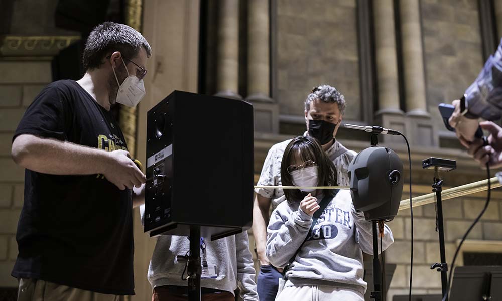 Two people hold measuring tape on Kodak Hall stage while another looks on.