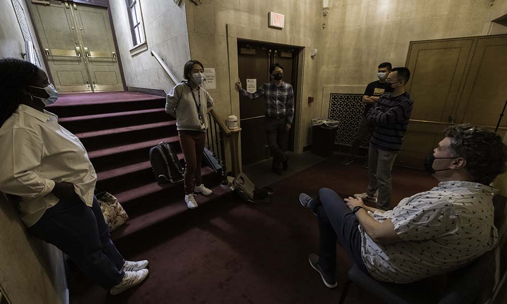 Several team members sitting, standing, around steps in a lobby.