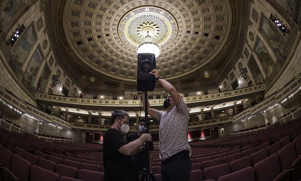 Two men adjust position of a speaker.