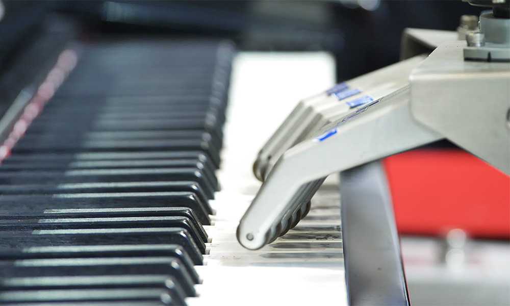 robot hands playing notes on piano keyboard.