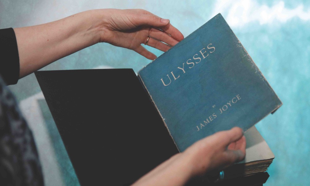 Two hands open a first edition book of Ulysses by James Joyce.