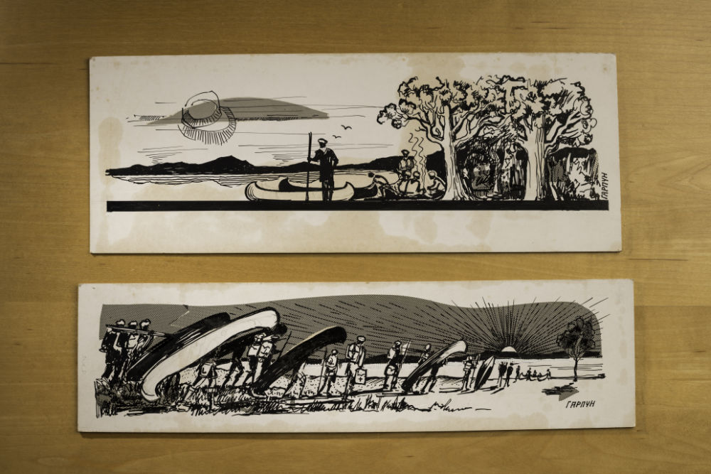 Two black-and-white drawings on a table of people in nature with canoes.