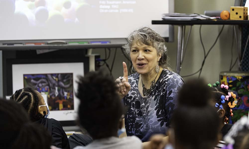 Sydney Greaves teaching arts integration lesson sitting on floor with children.