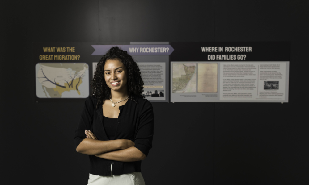 Brynn Murphy-Stanley in front of the Great Migration panel she created for the Clarissa Uprooted exhibit.