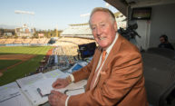 archival photo of Vin Scully in the broadcast booth.