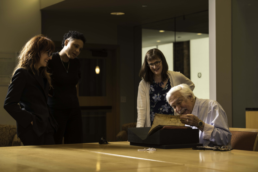 Four people around a medieval manuscript. 