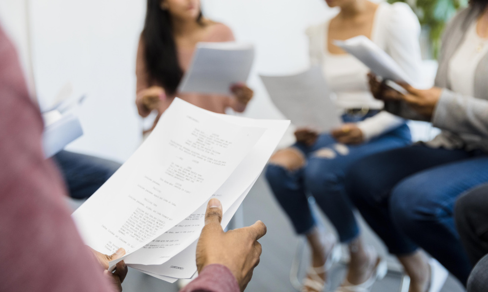 People sitting in a circle and holding scripts.