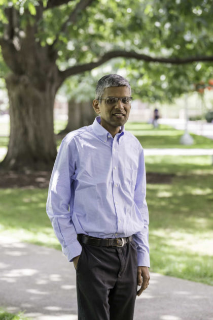 Ajay Anand smiles with one hand in his pocket for portrait outdoors.