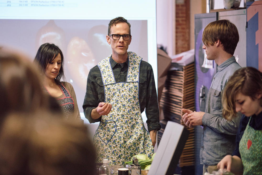 Cary Adams in an apron teaching students.