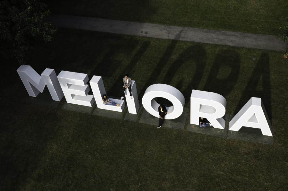 Aerial view of the MELIORA letters with people posing for photos on and near them. 