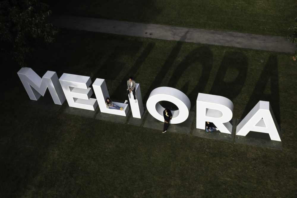 Aerial view of the MELIORA letters with people posing for photos on and near them.