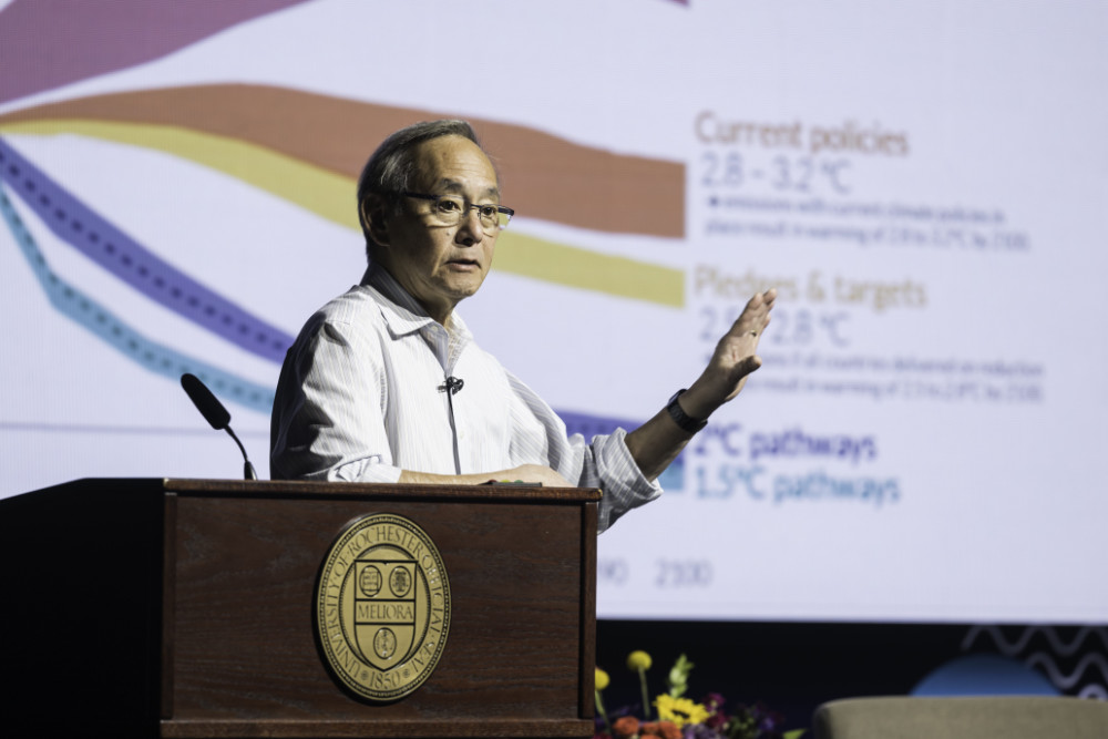 Steven Chu stands at a podium with a slide deck in the background.