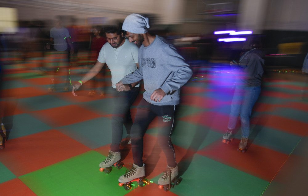 Two blurry people holding hands and roller skating on a red and green checkered rink.