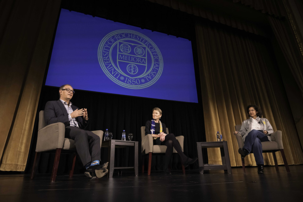 David Figlio, Sarah Mangelsdorf, and Lizette Pérez-Deisboeck seated on stage in front of a screen with the University of Rochester seal.