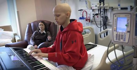 boy plays a keyboard inside a hospital room.