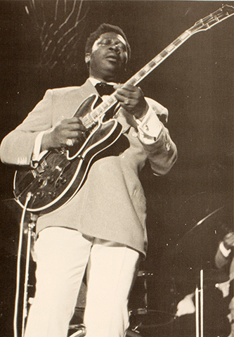 BB King plays the guitar on stage, basketball hoop in the background.