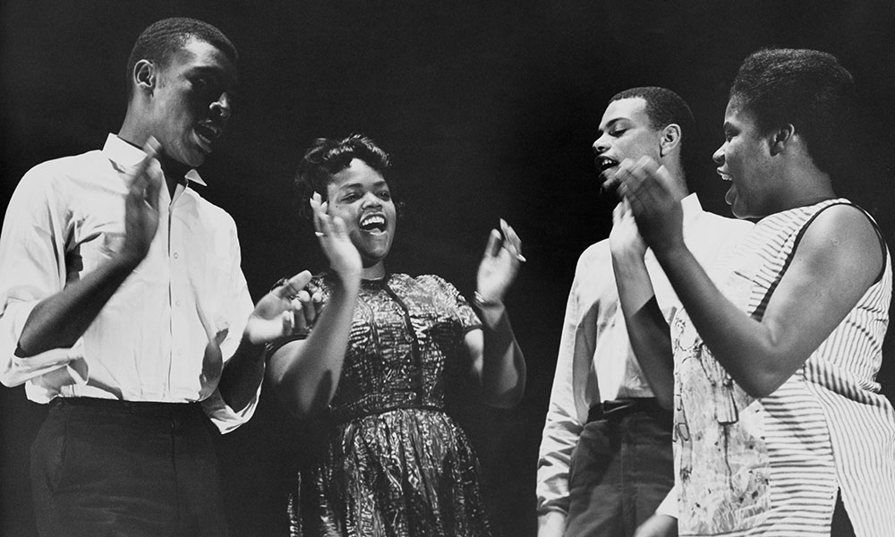 Black and white photo of the four members of Freedom Singers, four gospel musicians from Georgia, singing and clapping.