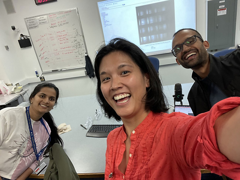 selfie with Jessica Shang and two students in the background in their lab.