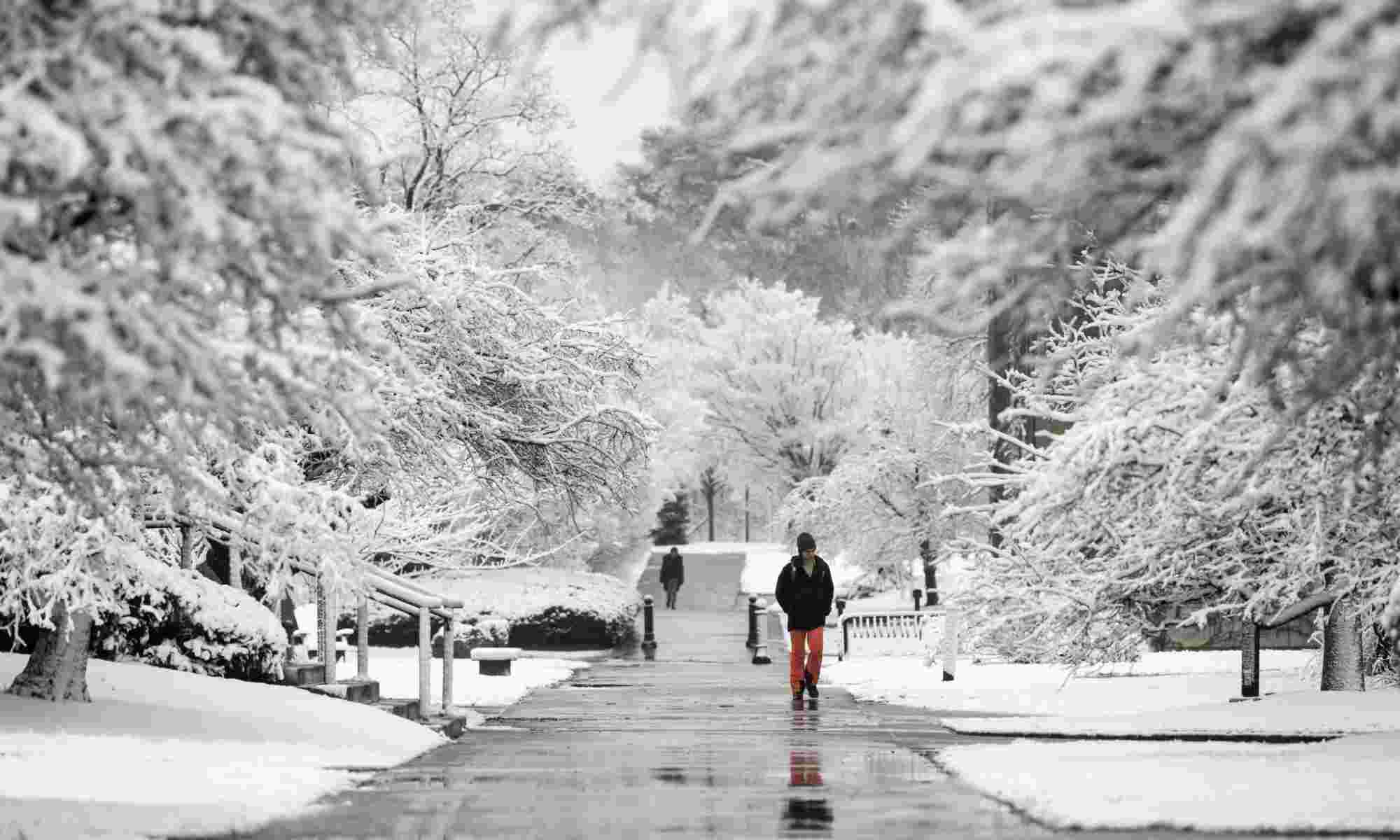 Person in red pants and black coat stands out in a campus scene covered in fresh white snow.
