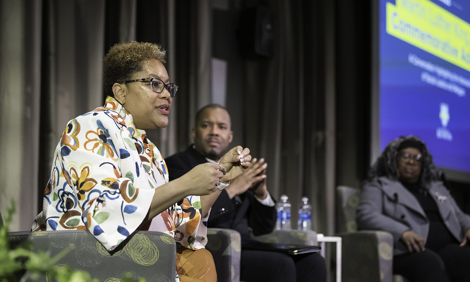 Feature image Three Black speakers seated on stage during a panel discussion.