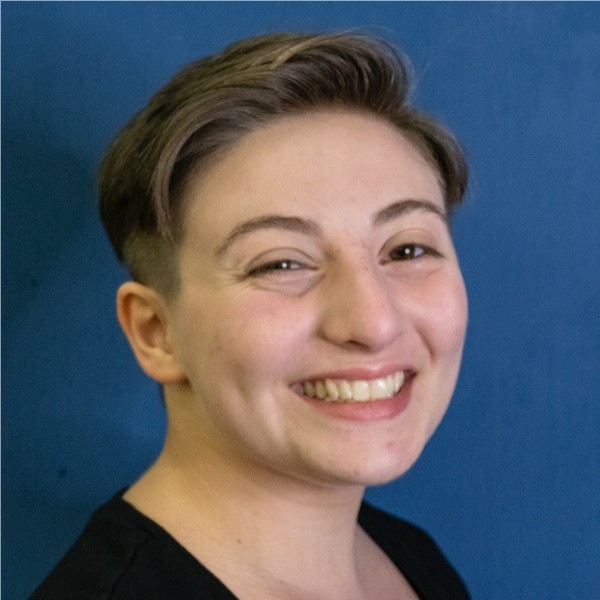 Close headshot of smiling student against blue background.