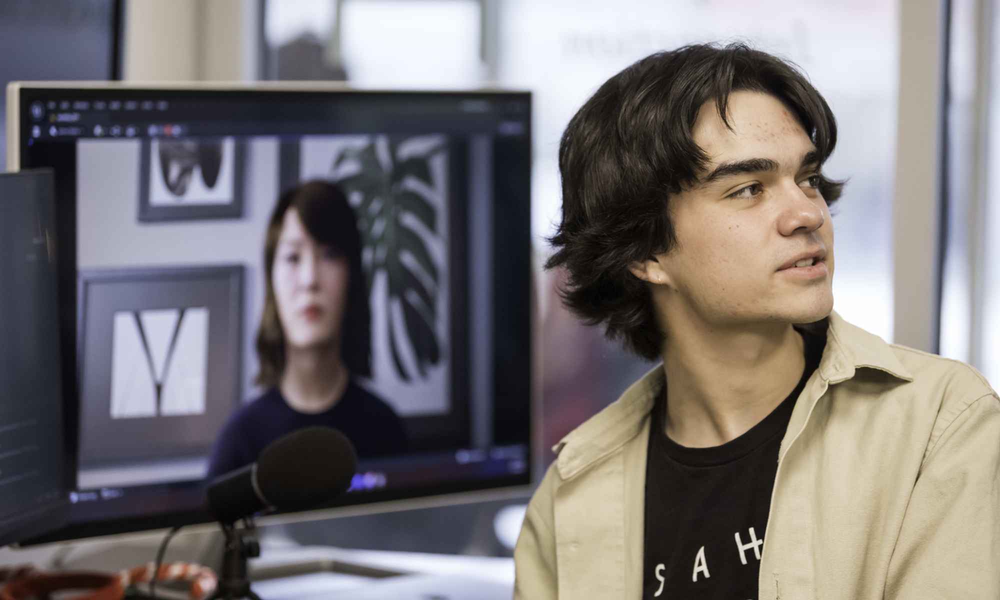 Undergraduate student in the Rochester Human-Computer Interaction lab seen with a computer screen displaying an AI avatar.