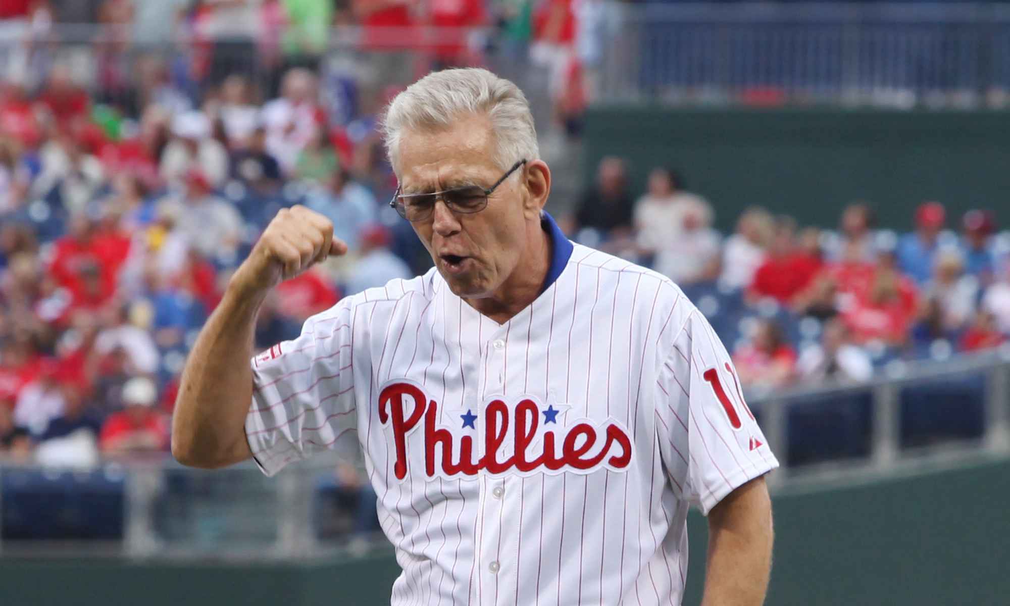 Feature image An elderly Tim McCarver fist pumps the air in a Phillies jersey
