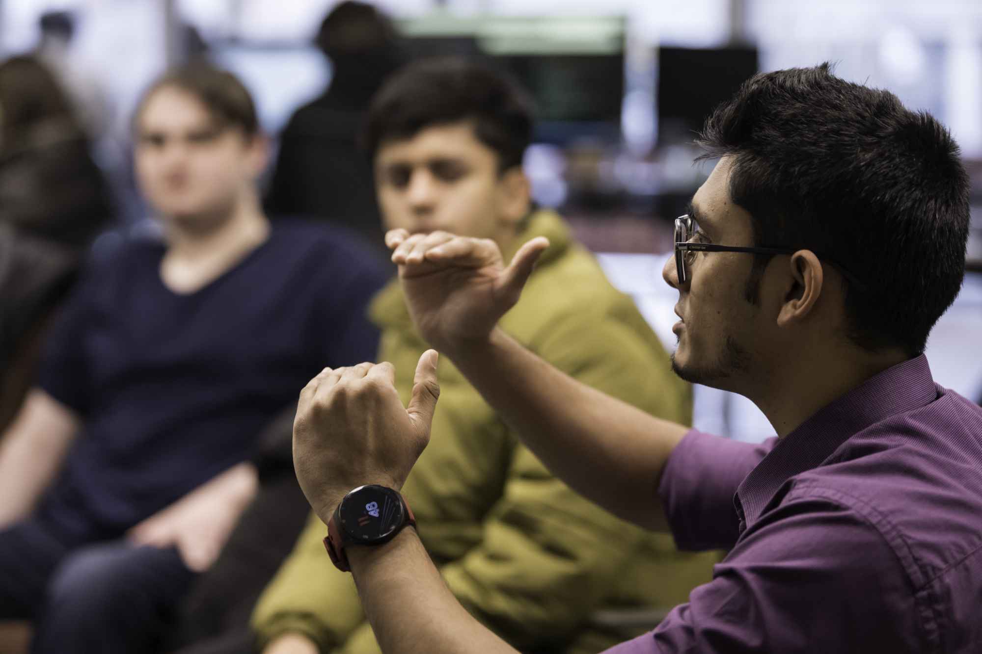 Rochester Human-Computer Interaction lab graduate student explains concepts to undergraduates, two o whom are seen out of focus in the background.