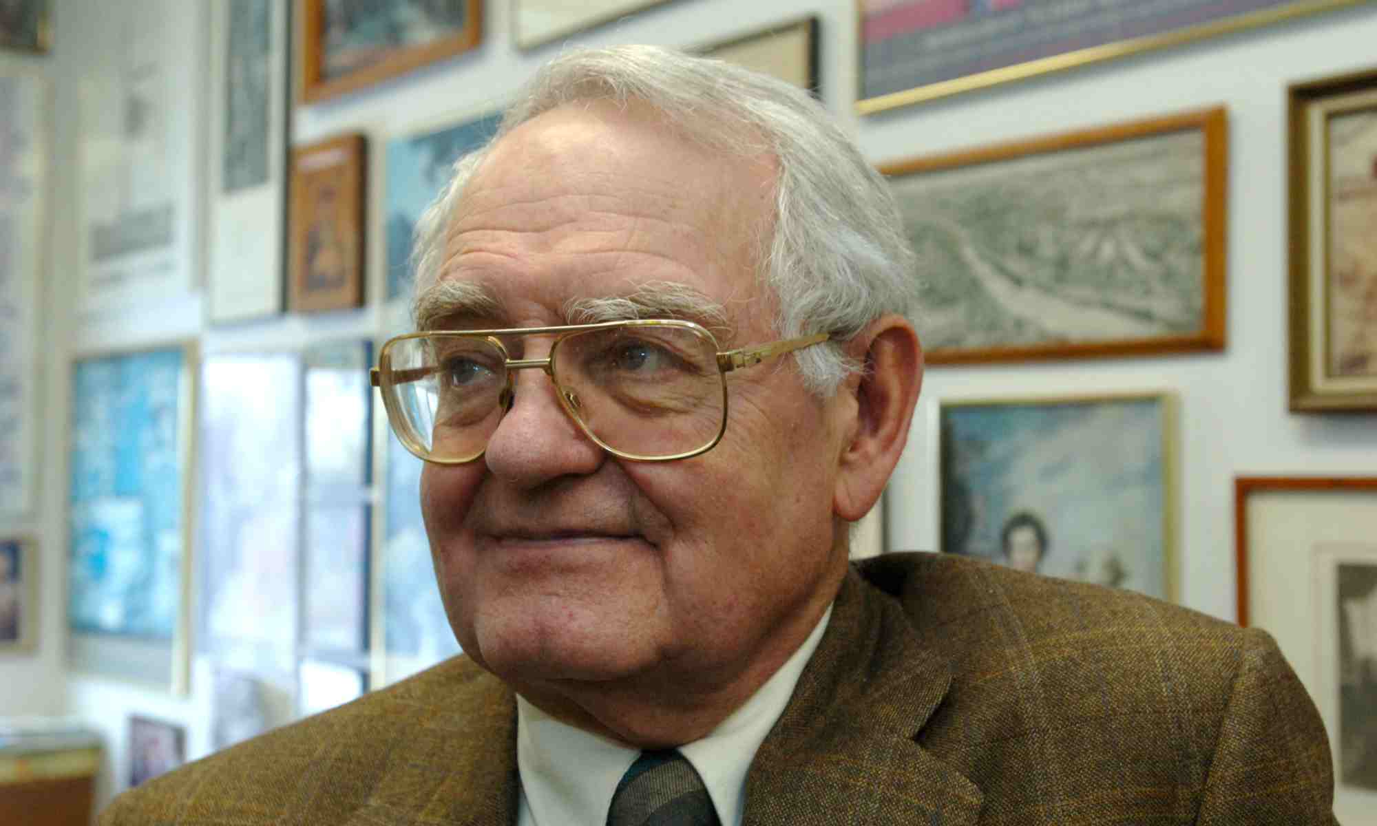 Close-up photo of Russell Peck in his office with wall art behind him.