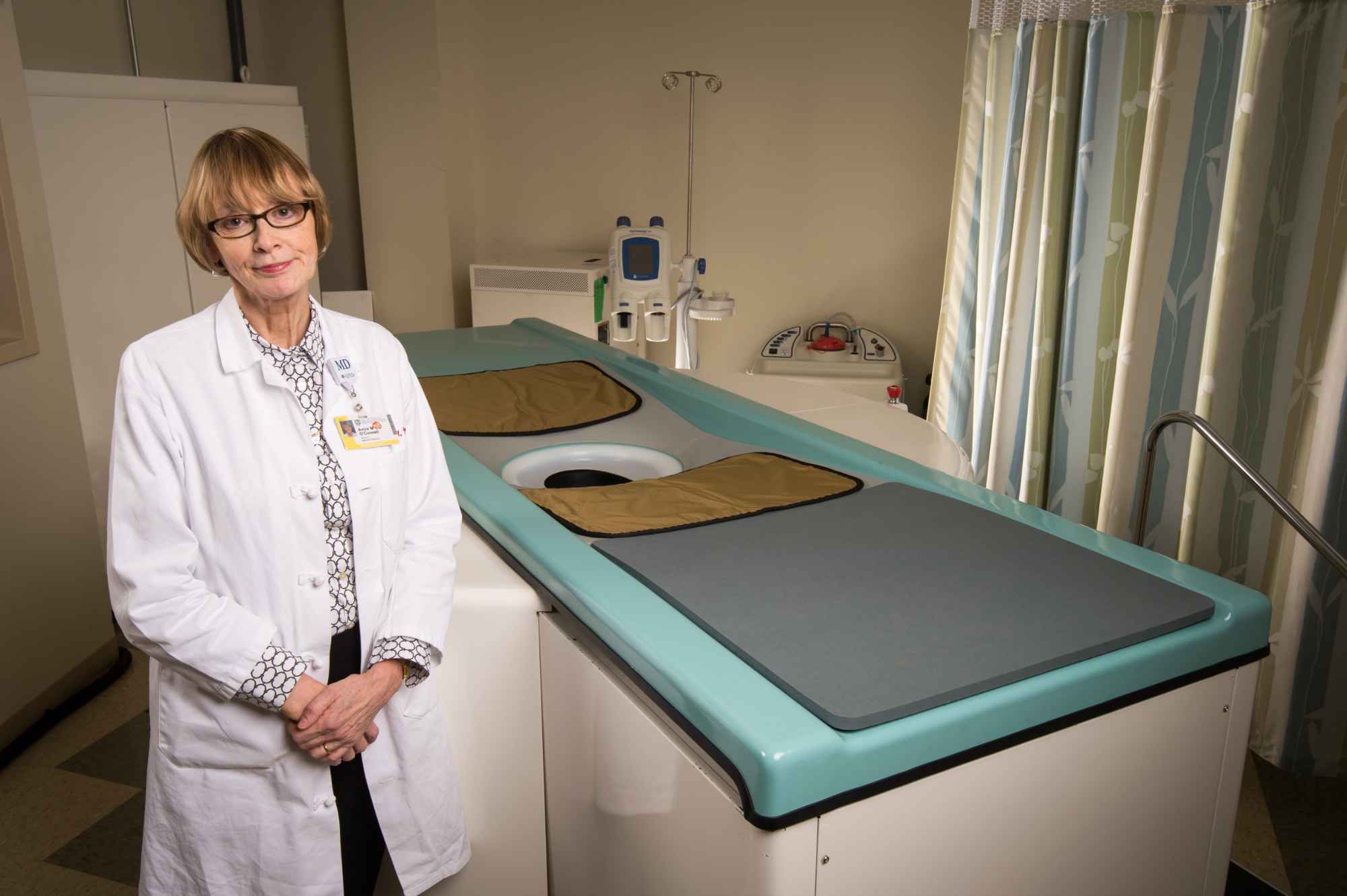 Avice O'Connell in a lab coat next top a breast imaging system.