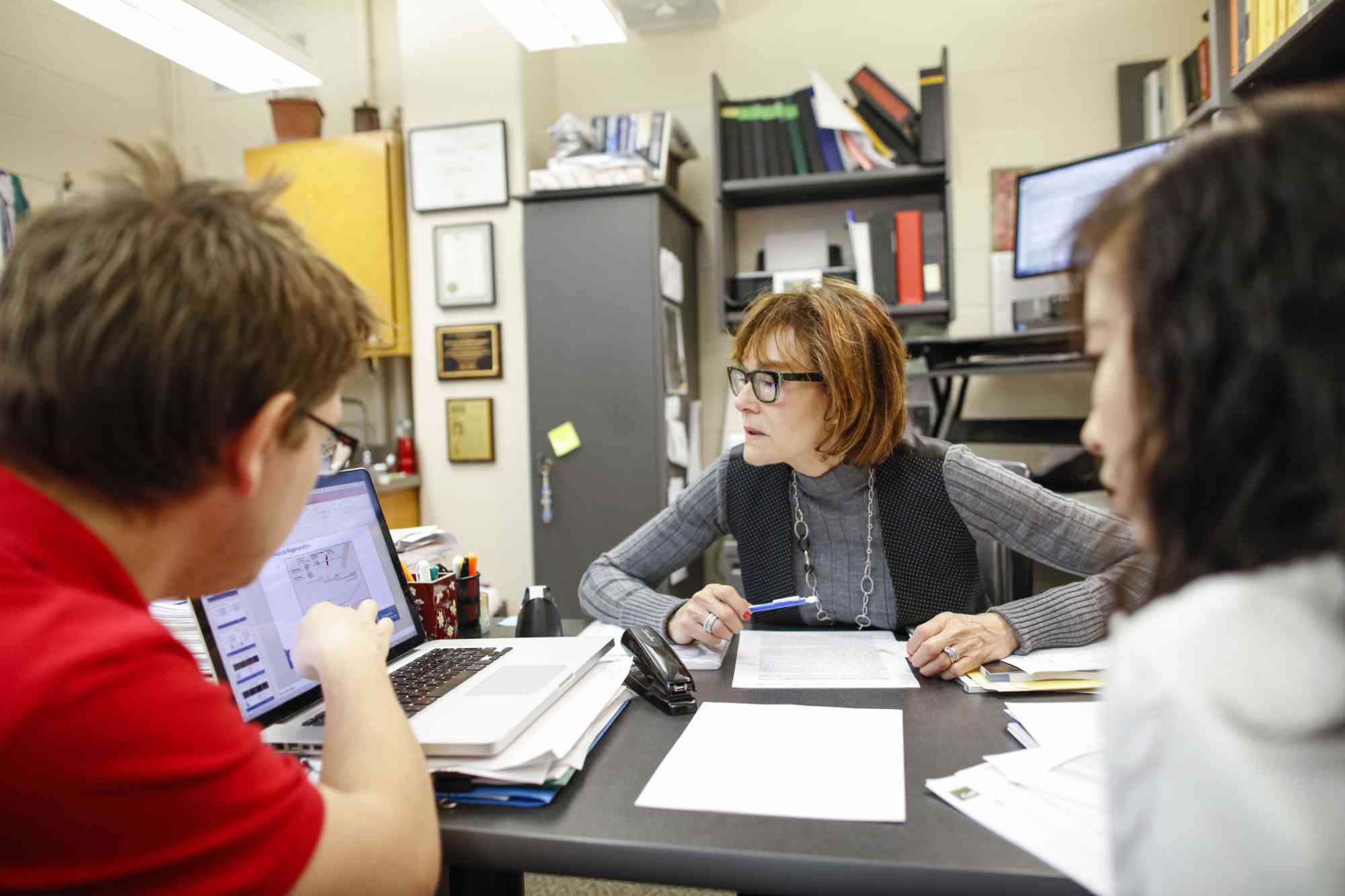 Lynne Maquat at a desk with two members of her lab.