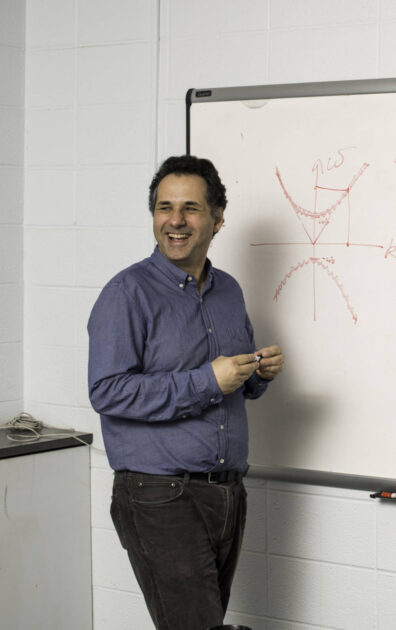 Miguel Alonso smile at a white board.