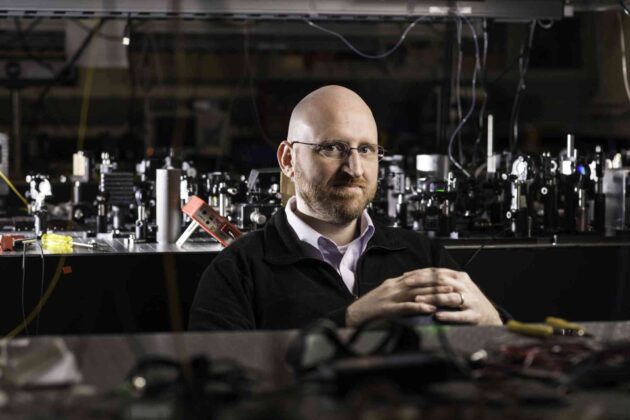 Will Renninger behind optics equipment in a lab.