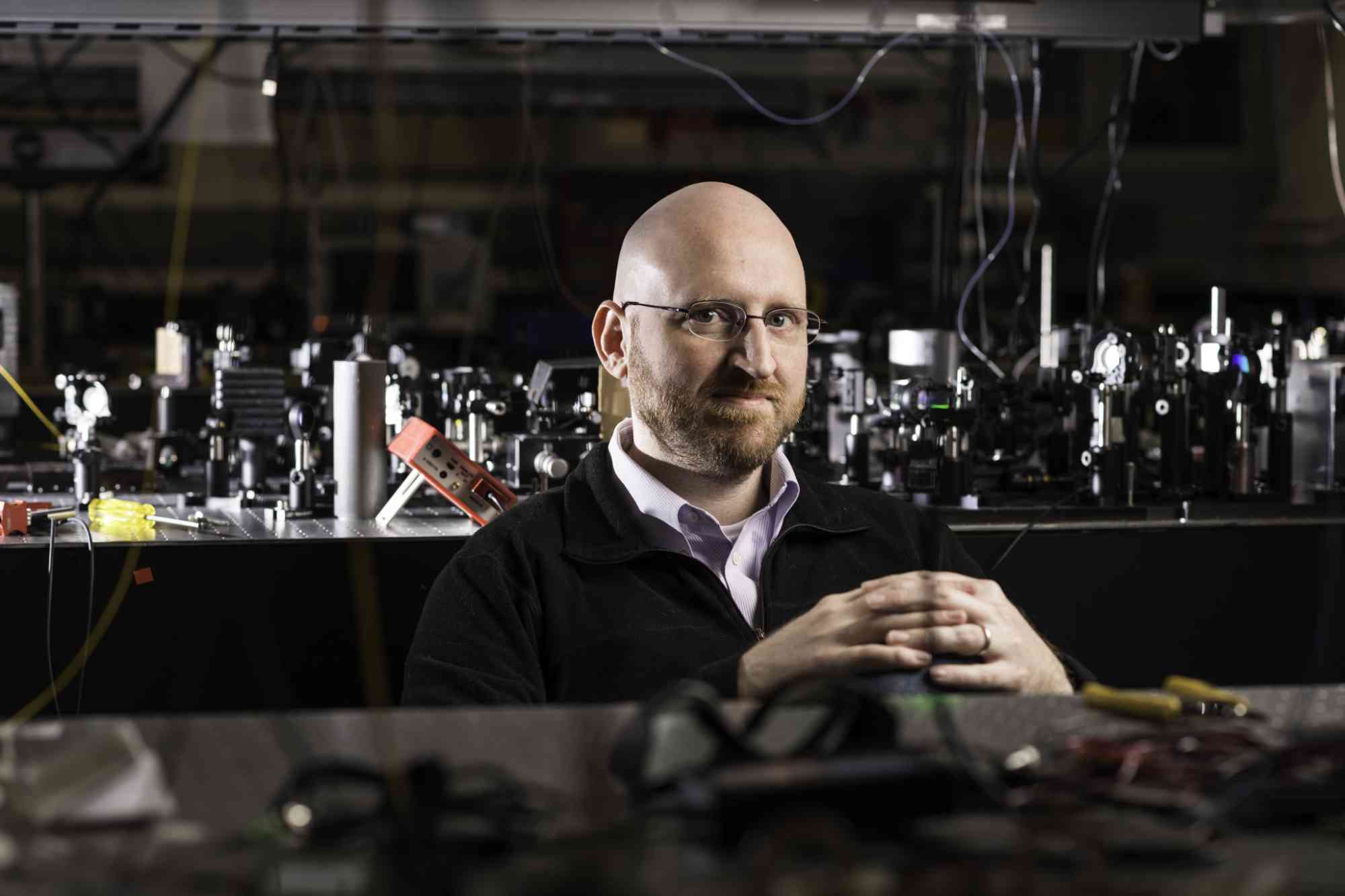 Will Renninger behind optics equipment in a lab. 